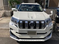 the front end of a white suv parked in a parking lot next to a building