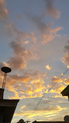 the sun is setting over some buildings and telephone poles in front of a cloudy sky