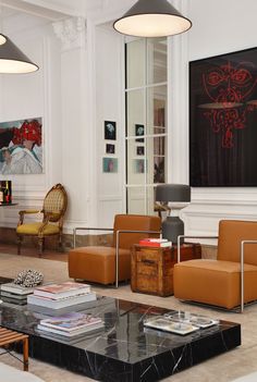 a living room filled with lots of furniture next to a fire place and paintings on the wall