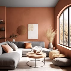 a living room with an orange wall and grey couches in front of a large window