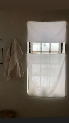 a window with white curtains and a towel hanging on the wall in front of it