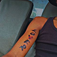 a man with a tattoo on his arm is sitting in a car and has the word faith written across it