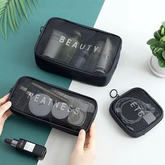 two black cosmetic bags sitting on top of a white table next to a green plant