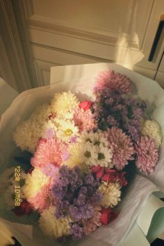 a bouquet of flowers sitting on top of a white paper bag in front of a door