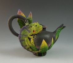 a ceramic figurine of a green and yellow lizard on top of a black vase