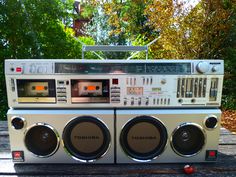 an old fashioned radio sitting on top of a wooden table in front of some trees