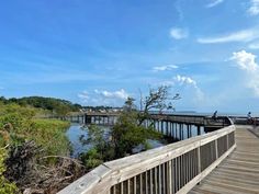 people are walking on a boardwalk over the water