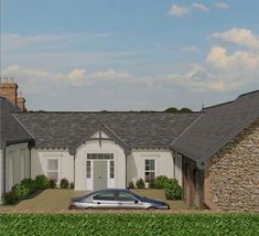 a car is parked in front of a house with a stone wall and green hedges