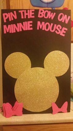 a sign that says pin the bow on minnie mouse with pink bows around its ears