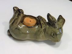 a ceramic animal candle holder with a lit candle in it