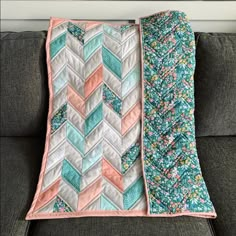 a quilted blanket sitting on top of a couch next to a gray sofa cushion