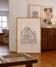 two framed pictures sitting on top of a hard wood floor next to a wooden table