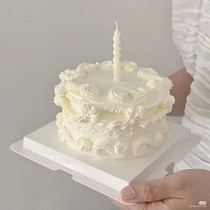 a woman holding a cake with a lit candle on it