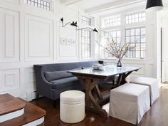 a living room filled with furniture and a wooden table in front of a white wall