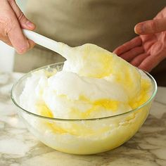 a person scooping ice cream into a glass bowl on top of a marble counter