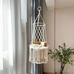 a cat is sleeping in a white hammock hanging from a window sill