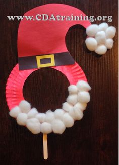 a paper plate wreath made to look like santa's hat with cotton balls on it