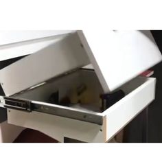 an open drawer on the side of a white cabinet with its lid opened to reveal something inside