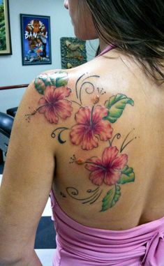 a woman wearing a pink dress with flowers on her shoulder and chest tattooing it's back