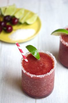 two glasses filled with red liquid and topped with a green leafy garnish