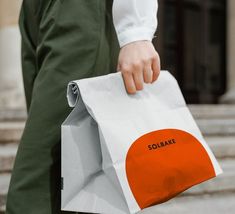 a person carrying a white bag with an orange circle on it and the words solbake printed on it