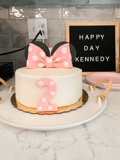 a minnie mouse cake with pink and white polka dots on it, sitting on a counter