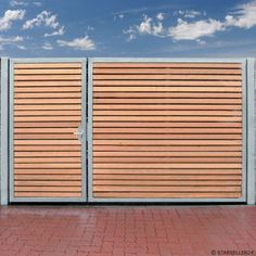 a wooden fence with metal bars on the top and bottom, in front of a blue sky