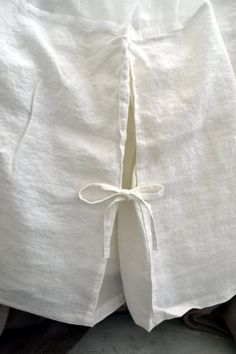 the back of a bed with white linens and ties tied to it's sides