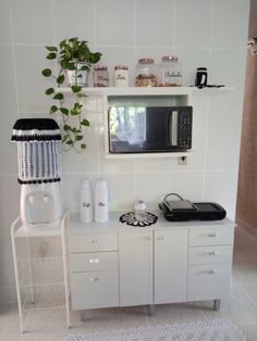 a microwave oven sitting on top of a white cabinet next to a potted plant