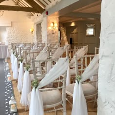 rows of chairs with white sashes and flowers on them