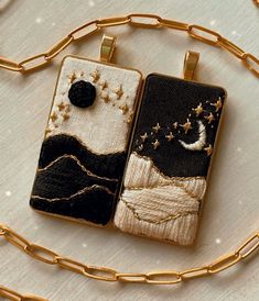 two pendants are sitting on a chain with stars and the moon in the sky