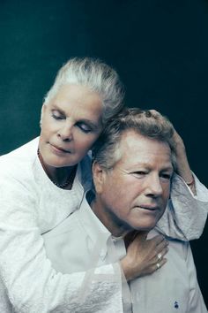 an older man and woman are posing for a photo in front of a black background