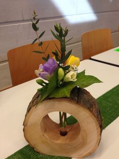 a wooden vase with flowers in it sitting on top of a green table runnering