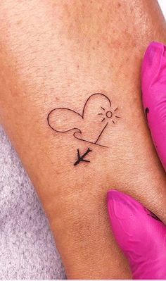 a woman's arm with a small heart and an arrow tattoo on the wrist