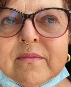 an older woman wearing glasses with a nose piercing