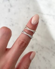 a woman's hand holding a ring with three rows of diamonds on top of it