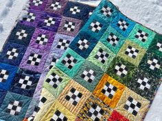 two quilts are laying in the snow on top of each other, one has a checkerboard design