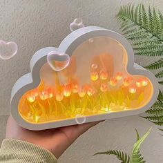 a person holding up a glowing cloud shaped object with flowers in the center and bubbles floating around it