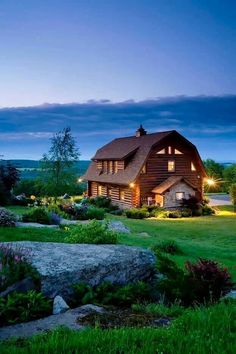 a large log house lit up at night in the evening with lights shining on it's windows