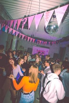 a group of people standing around each other in a room with bunting and flags