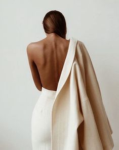 the back of a woman in a white dress with a shawl draped over her shoulders