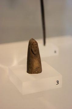 a small object is on display in a museum setting with a hammer sticking out of it's head