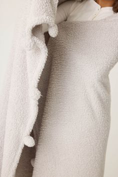 a woman in a white robe is holding her head up to the side while she covers her face with a blanket