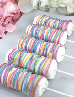 colorful candy lollipops are lined up on a white table next to flowers