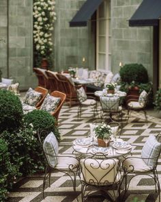 an outdoor dining area with tables and chairs, potted plants on either side of the table