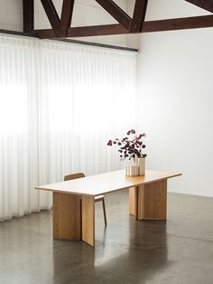 a wooden table sitting in front of a window next to a vase filled with flowers