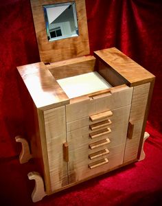 a wooden box with drawers and a mirror on top of it in front of a red background