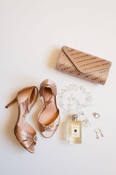 a pair of high heeled shoes next to a purse and some jewelry on a white surface