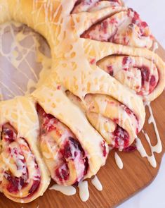 a pastry with white icing and cranberry filling on a wooden platter