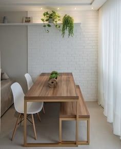 a wooden table sitting in front of a white brick wall with plants on the top